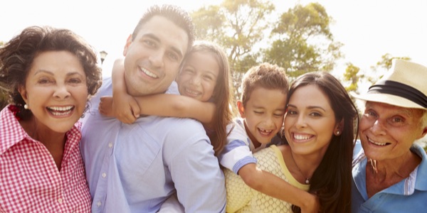 a Latin family hugging, smiling, and staring at the camera